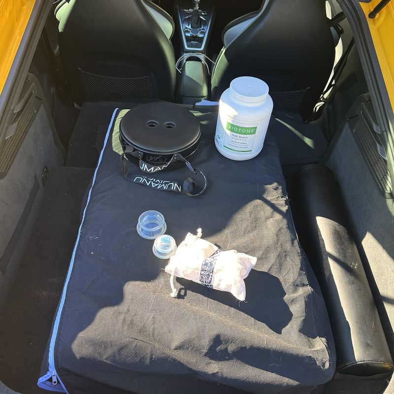 The back of Brooke's car packed with a folded massage table, bolster, lotion and cups